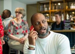 A man in a coffee shop talking into a mobile phone