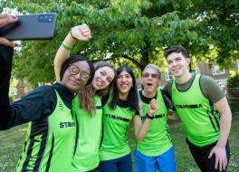 Three women and two men in running outfits posing for a selfie photograph taken by one of the women