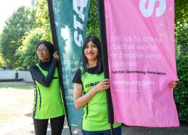 Two women in running outfits holding flags and looking at the camera