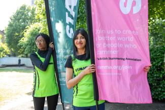 Two women in running outfits holding flags and looking at the camera