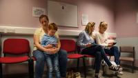 Mothers with children on their laps sitting in a doctor's waiting room