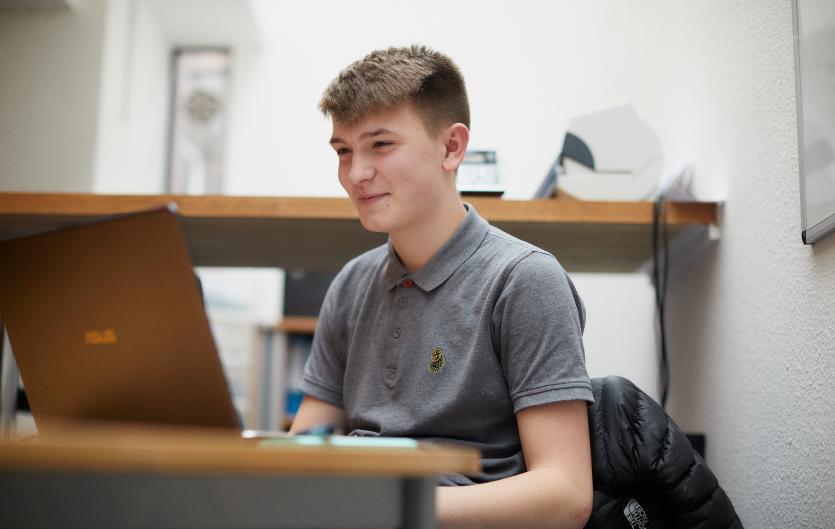 Online A teenaged boy typing on a laptop