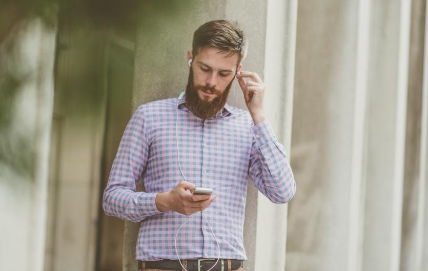 Apps and devices Man holding a mobile phone and putting in an earpiece