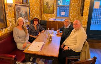 Four people sitting round a pub table smiling for the camera